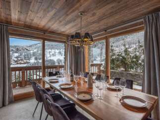 This dining area boasts rustic charm with its wooden ceiling and large windows showcasing a snowy mountain view.