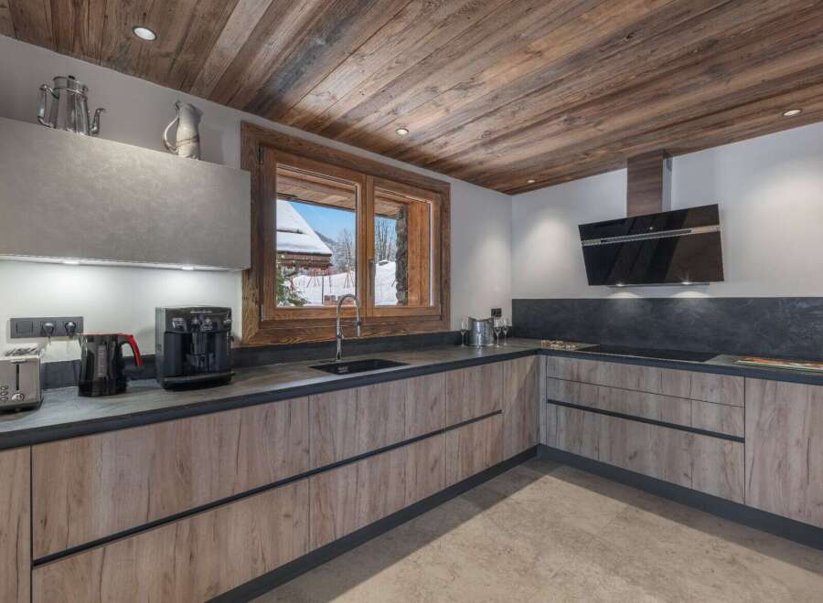 This kitchen features wooden cabinets with sleek, modern hardware and a dark countertop that contrasts beautifully with the light walls.