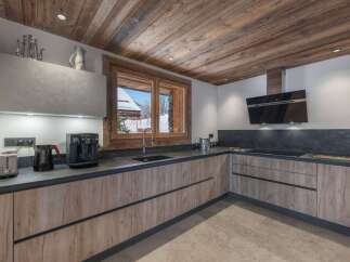 This kitchen features wooden cabinets with sleek, modern hardware and a dark countertop that contrasts beautifully with the light walls.