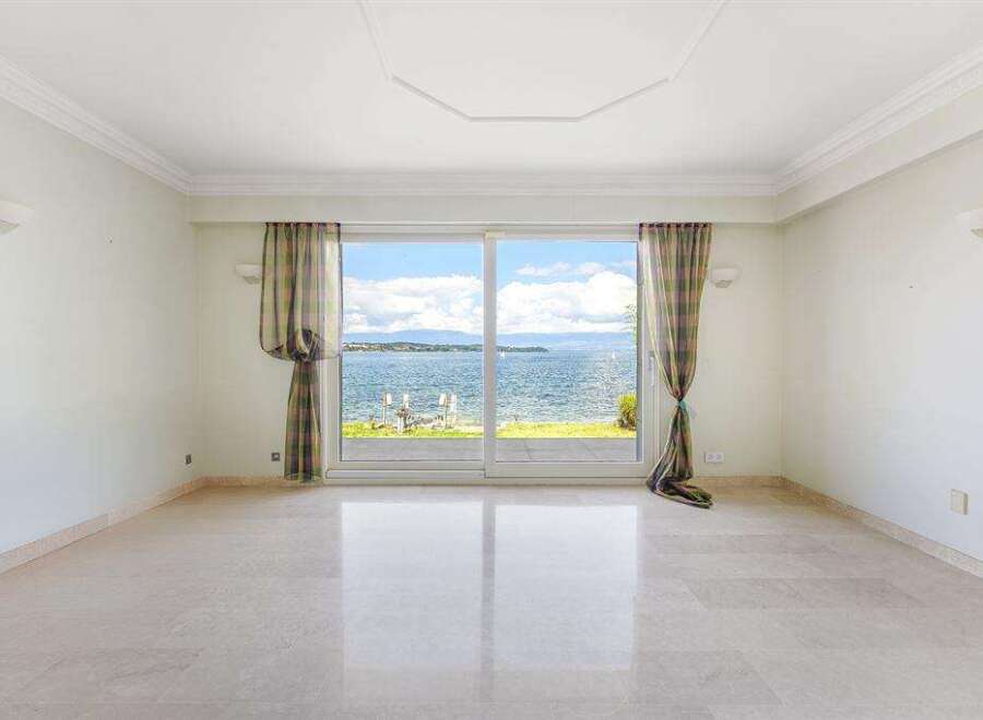 This stunning room boasts a breathtaking waterfront view, framed by elegant curtains and a large sliding glass door.