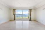 This stunning room boasts a breathtaking waterfront view, framed by elegant curtains and a large sliding glass door.