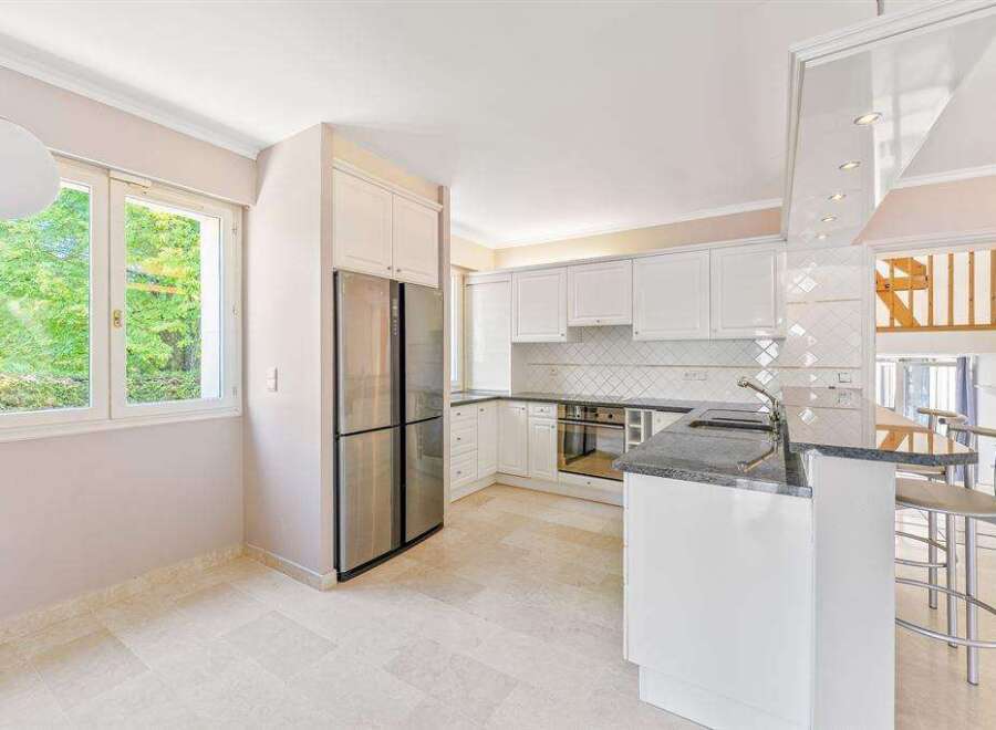 This bright and airy kitchen features white cabinets, stainless steel appliances, and a breakfast bar perfect for casual dining.