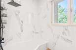This is a modern bathroom featuring white marble-patterned walls and a matching white bathtub.