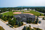 Discover this charming apartment complex with a view of a sports field and water tower, nestled near lush trees.