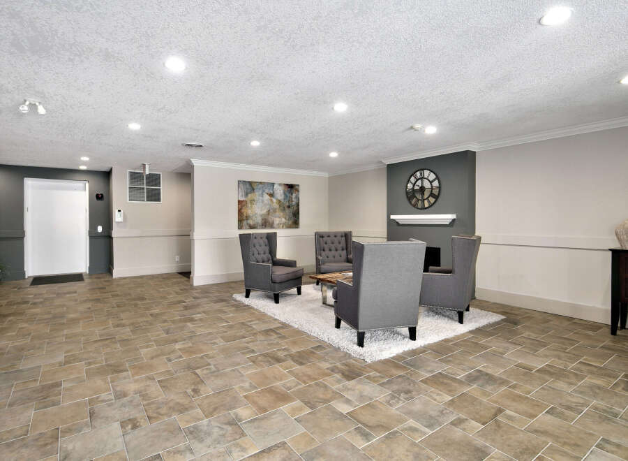 This inviting lounge area features stylish gray armchairs arranged around a modern coffee table, set upon a plush white rug.