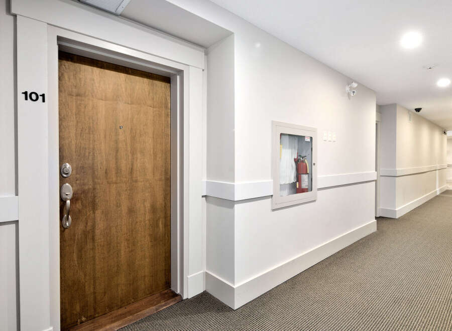 A well-lit hallway in a modern apartment building features neutral tones and clean lines.