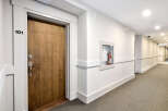 A well-lit hallway in a modern apartment building features neutral tones and clean lines.