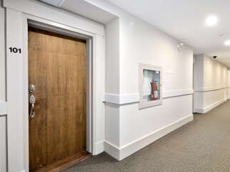 A well-lit hallway in a modern apartment building features neutral tones and clean lines.