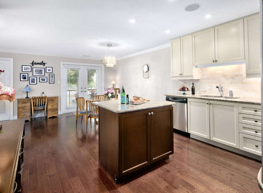 This inviting kitchen boasts a central island with granite countertops, complemented by cream-colored cabinetry and stainless steel appliances.