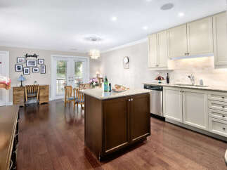 This inviting kitchen boasts a central island with granite countertops, complemented by cream-colored cabinetry and stainless steel appliances.