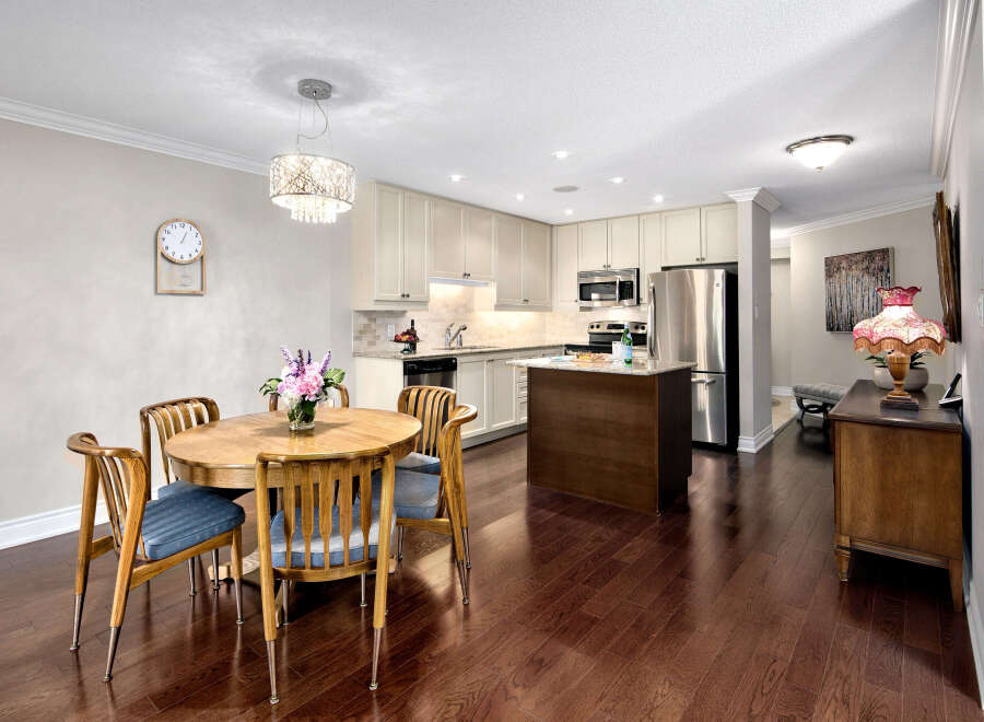 This inviting kitchen and dining area features warm wood flooring that complements the wooden table and chairs.