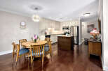 This inviting kitchen and dining area features warm wood flooring that complements the wooden table and chairs.