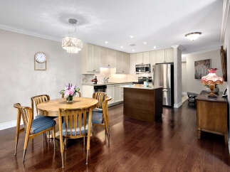 This inviting kitchen and dining area features warm wood flooring that complements the wooden table and chairs.