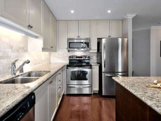 This stunning kitchen boasts granite countertops, stainless steel appliances, and ample storage space with its stylish white cabinets.