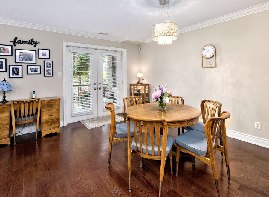 This inviting dining area features rich hardwood floors, a charming round wooden table with blue cushioned chairs, and a stylish chandelier.