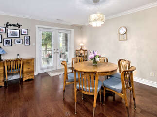 This inviting dining area features rich hardwood floors, a charming round wooden table with blue cushioned chairs, and a stylish chandelier.