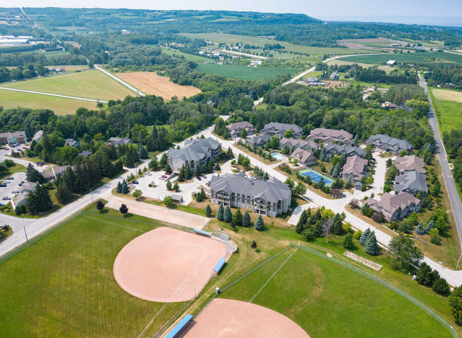 This aerial view showcases a beautifully landscaped real estate development nestled in a vibrant community, complete with well-maintained baseball fields and lush greenery.