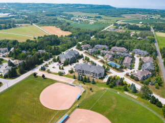 This aerial view showcases a beautifully landscaped real estate development nestled in a vibrant community, complete with well-maintained baseball fields and lush greenery.