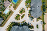 An aerial view captures a well-maintained property featuring a swimming pool, tennis court, and ample parking.