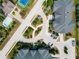 An aerial view captures a well-maintained property featuring a swimming pool, tennis court, and ample parking.