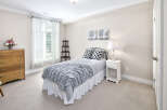 This cozy bedroom features a comfortable bed with stylish grey and white linens, complemented by matching throw pillows.