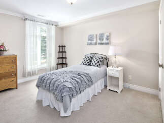 This cozy bedroom features a comfortable bed with stylish grey and white linens, complemented by matching throw pillows.