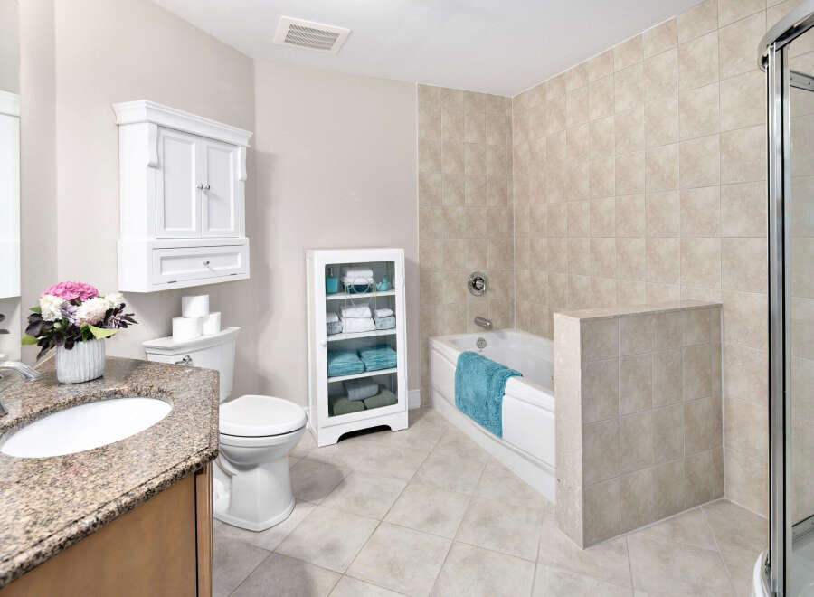 This bathroom features a tiled shower and bathtub combination, creating a spa-like retreat.