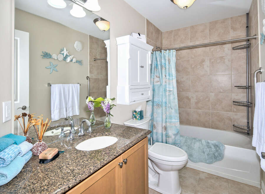 This bathroom boasts a beach-inspired theme with seashell decorations and a coordinating shower curtain.