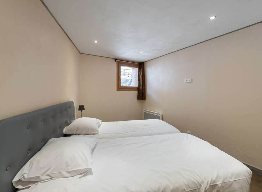 This cozy bedroom features two twin beds with crisp white linens, perfect for guests or a shared living space.