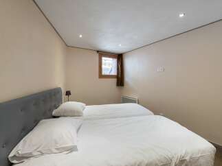 This cozy bedroom features two twin beds with crisp white linens, perfect for guests or a shared living space.