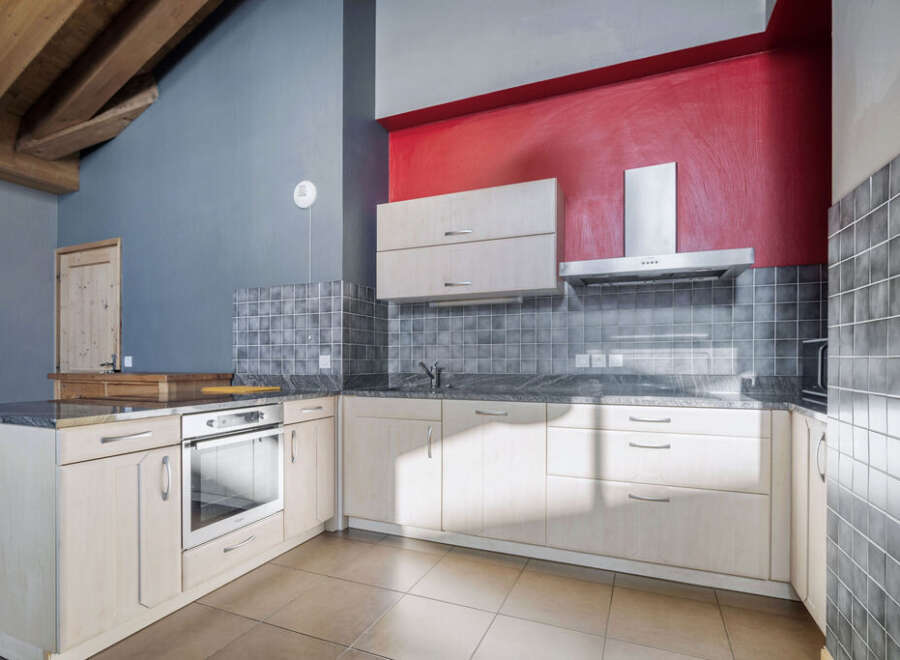 This stunning kitchen boasts a modern design with sleek cabinetry and a vibrant red accent wall.