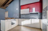 This stunning kitchen boasts a modern design with sleek cabinetry and a vibrant red accent wall.