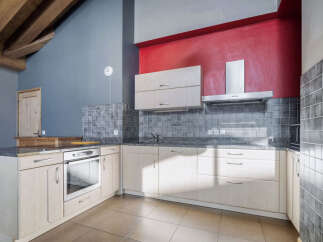 This stunning kitchen boasts a modern design with sleek cabinetry and a vibrant red accent wall.