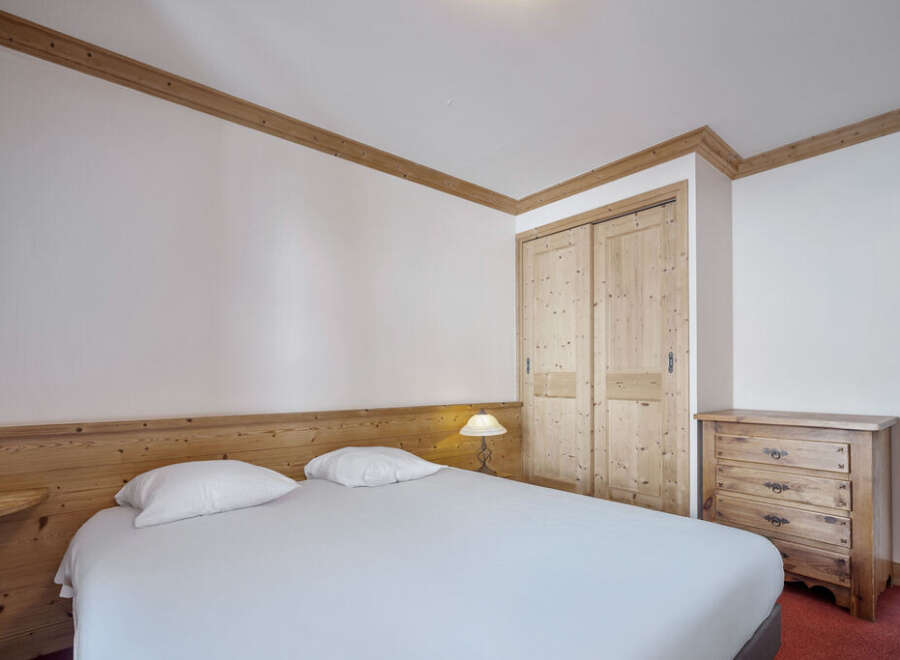 Discover the charm of this cozy bedroom, featuring a comfortable bed and ample storage.