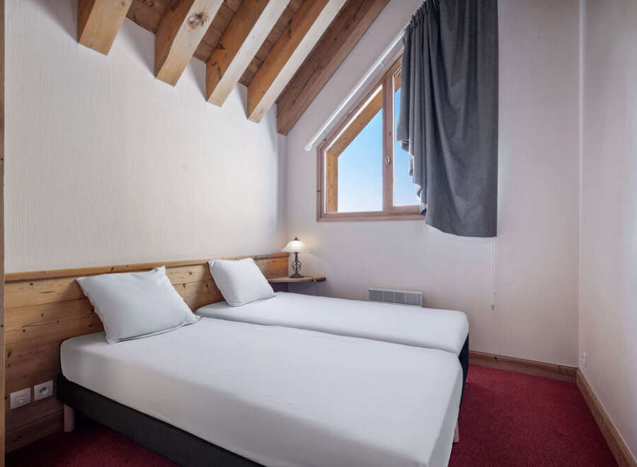 This cozy bedroom features two twin beds with crisp white linens, perfect for a comfortable stay.