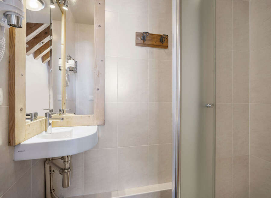 This charming bathroom features a unique wooden-framed mirror and a modern corner sink, creating a stylish and functional space.