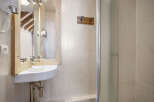 This charming bathroom features a unique wooden-framed mirror and a modern corner sink, creating a stylish and functional space.