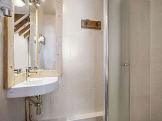This charming bathroom features a unique wooden-framed mirror and a modern corner sink, creating a stylish and functional space.