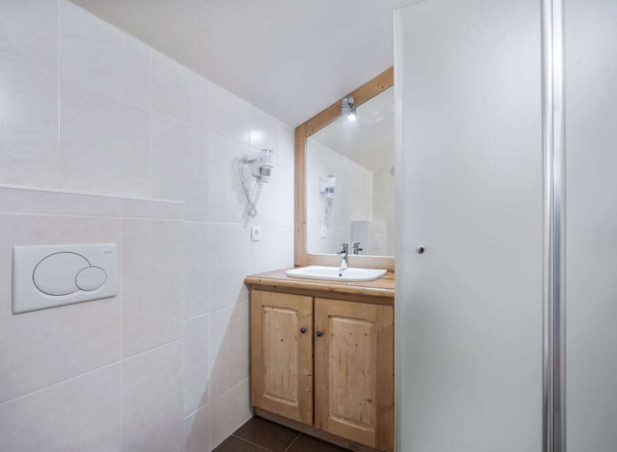 This bathroom features a stylish wooden vanity with a sleek sink, offering ample storage and a touch of rustic charm.