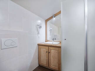 This bathroom features a stylish wooden vanity with a sleek sink, offering ample storage and a touch of rustic charm.