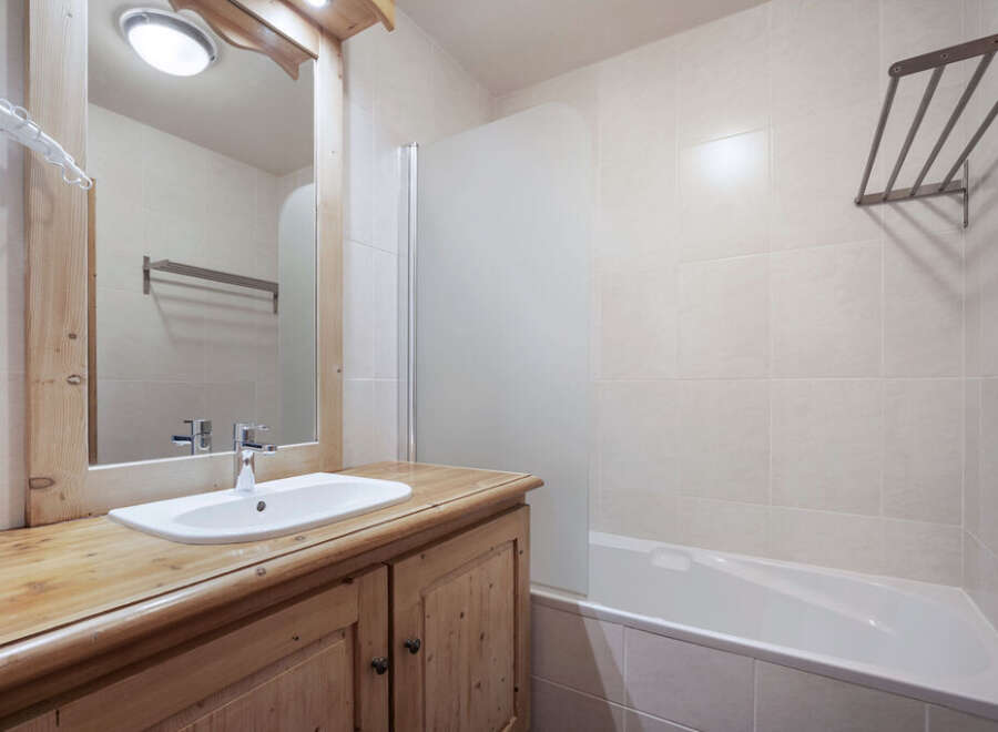 This charming bathroom features a rustic wooden vanity and a sleek white sink, offering a blend of style and functionality.