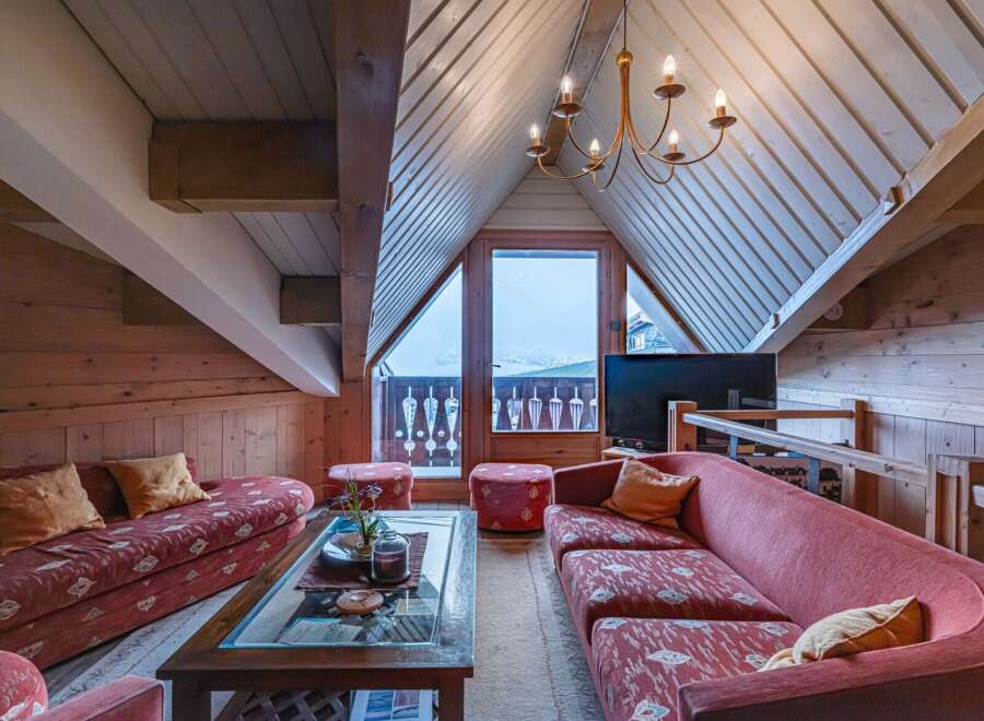 Experience the charm of this cozy attic living space, featuring a unique sloped ceiling and exposed wooden beams.