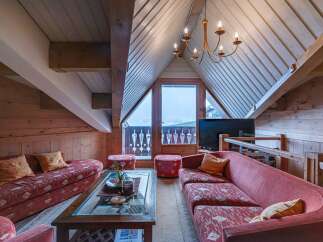 Experience the charm of this cozy attic living space, featuring a unique sloped ceiling and exposed wooden beams.