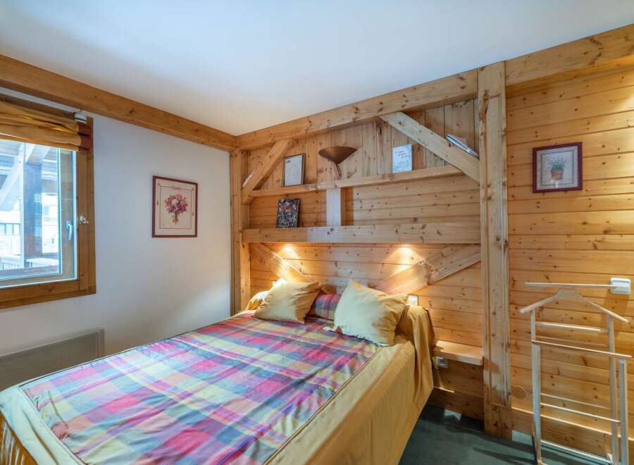 This cozy bedroom features a rustic wooden headboard and walls, creating a warm and inviting atmosphere.