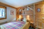 This cozy bedroom features a rustic wooden headboard and walls, creating a warm and inviting atmosphere.
