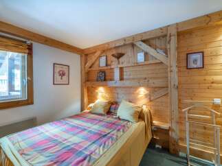 This cozy bedroom features a rustic wooden headboard and walls, creating a warm and inviting atmosphere.