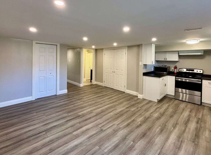 This inviting space features a modern kitchen with sleek white cabinetry and stainless steel appliances.