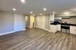 This inviting space features a modern kitchen with sleek white cabinetry and stainless steel appliances.