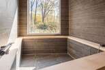 Experience tranquility in this luxurious bathroom, featuring a stunning view of nature through a large window.