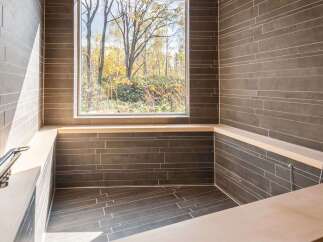 Experience tranquility in this luxurious bathroom, featuring a stunning view of nature through a large window.